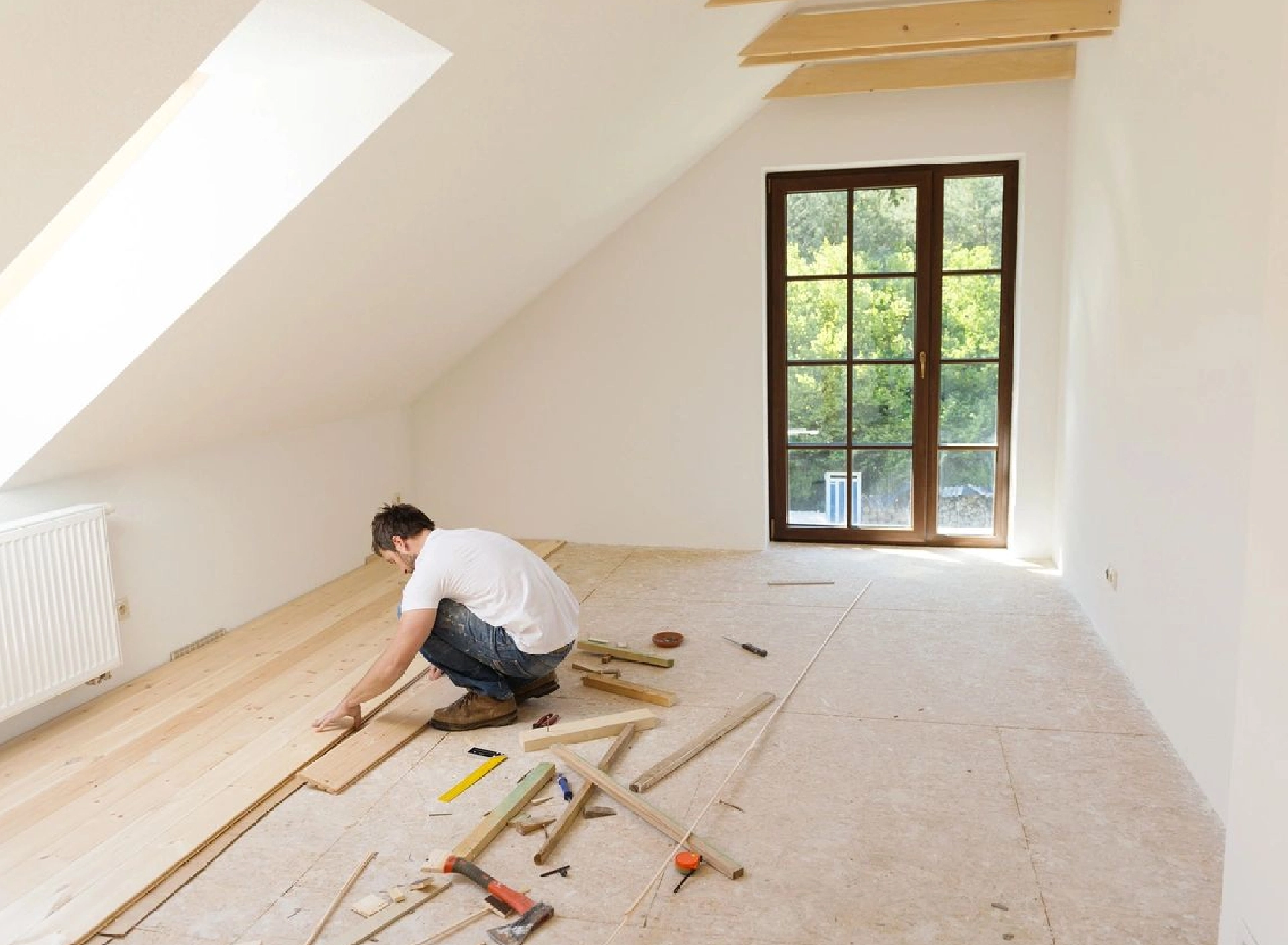 A man is laying down some wood in the floor