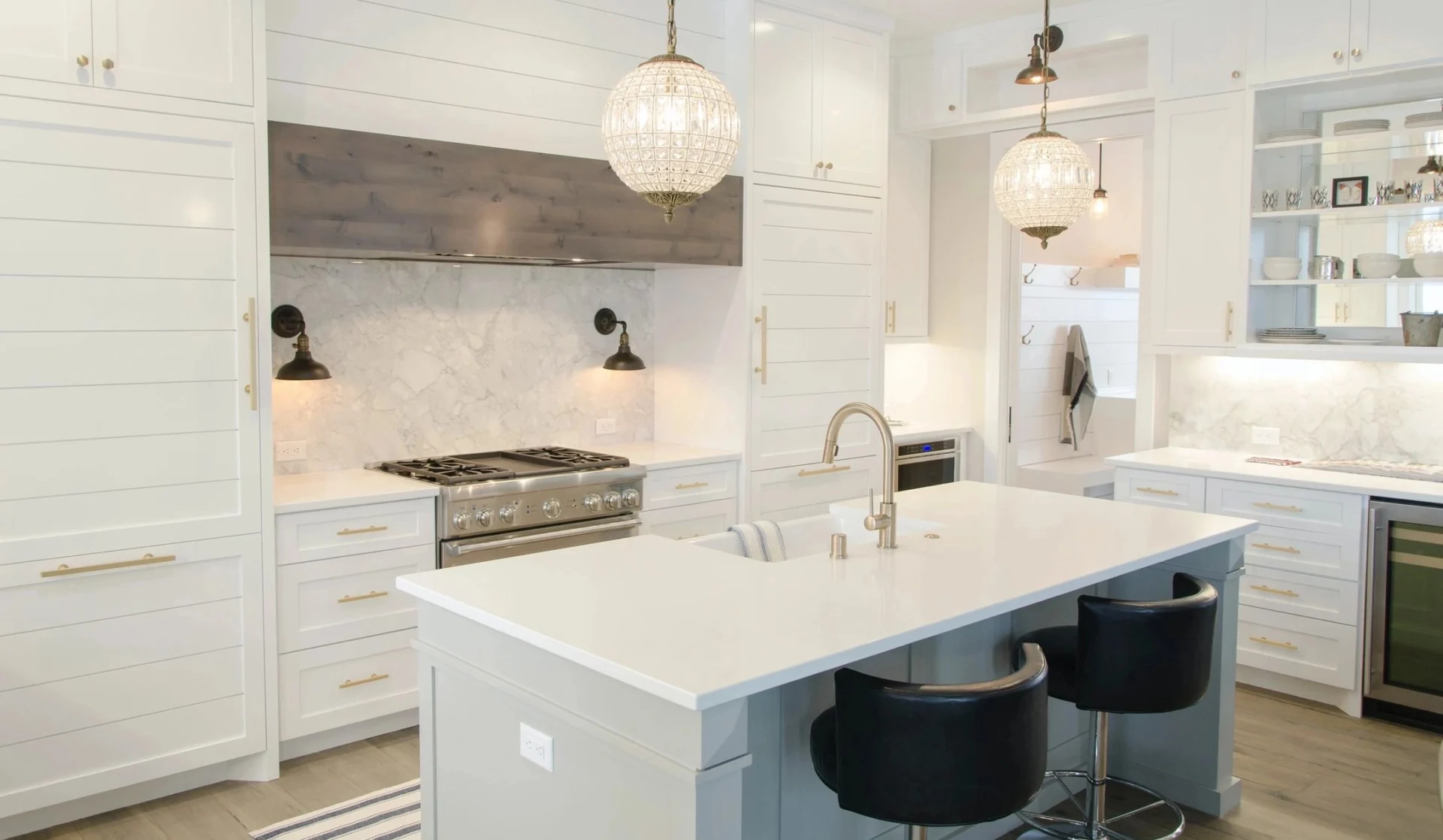 A kitchen with white cabinets and black stools.