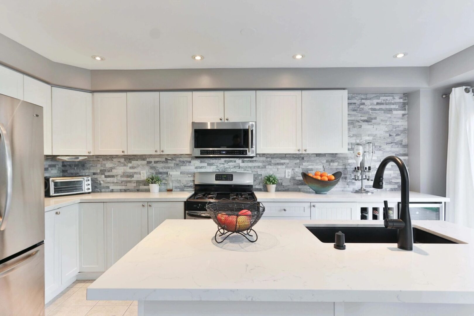 A kitchen with white cabinets and black appliances.